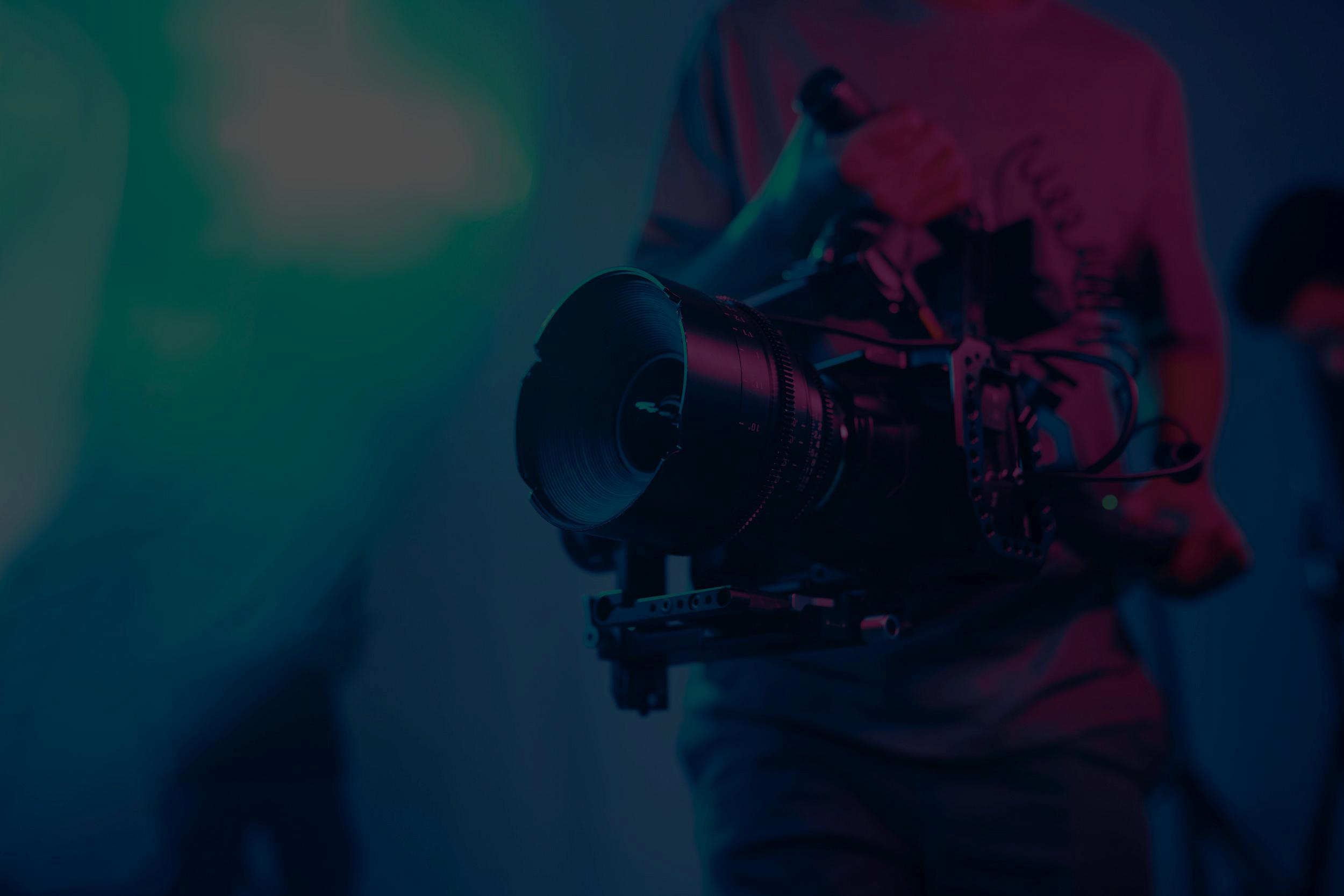 camera-operator-holds-professional-camera-with-lar-2026-03-24-07-15-20-utc (1) Design Gráfico para Evento